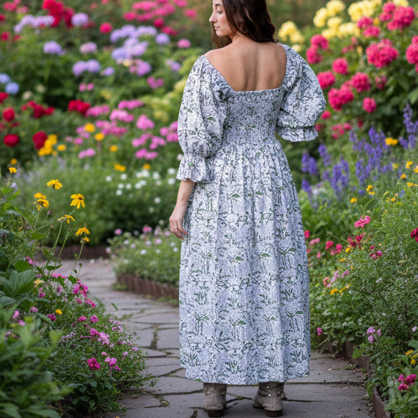 Woman in a floral dress standing in a forest during sunset