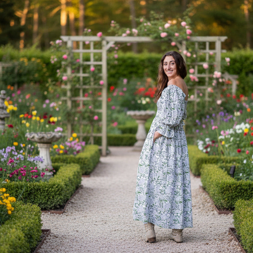 Woman in a floral dress standing in a forest during sunset
