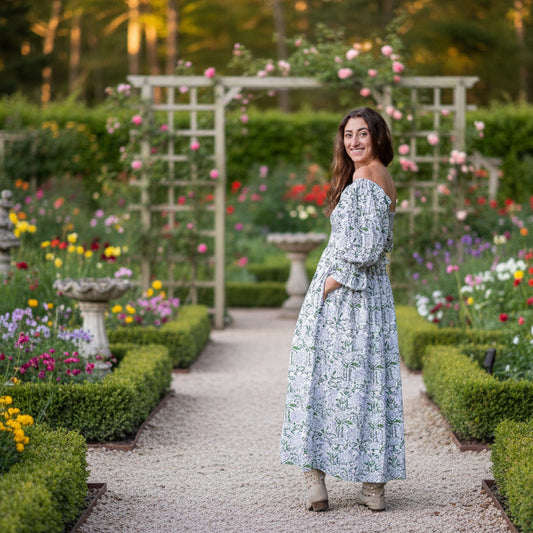 Woman in a floral dress standing in a forest during sunset