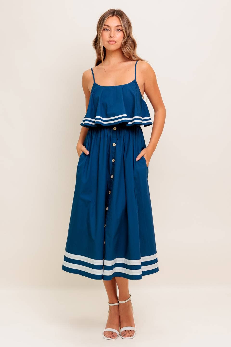 Woman wearing a blue dress with white stripes on a plain background