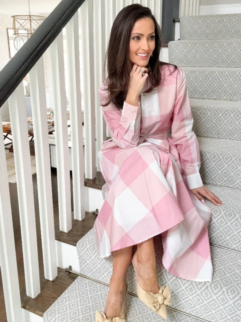 Woman in a pink and white checkered dress sitting on a staircase.